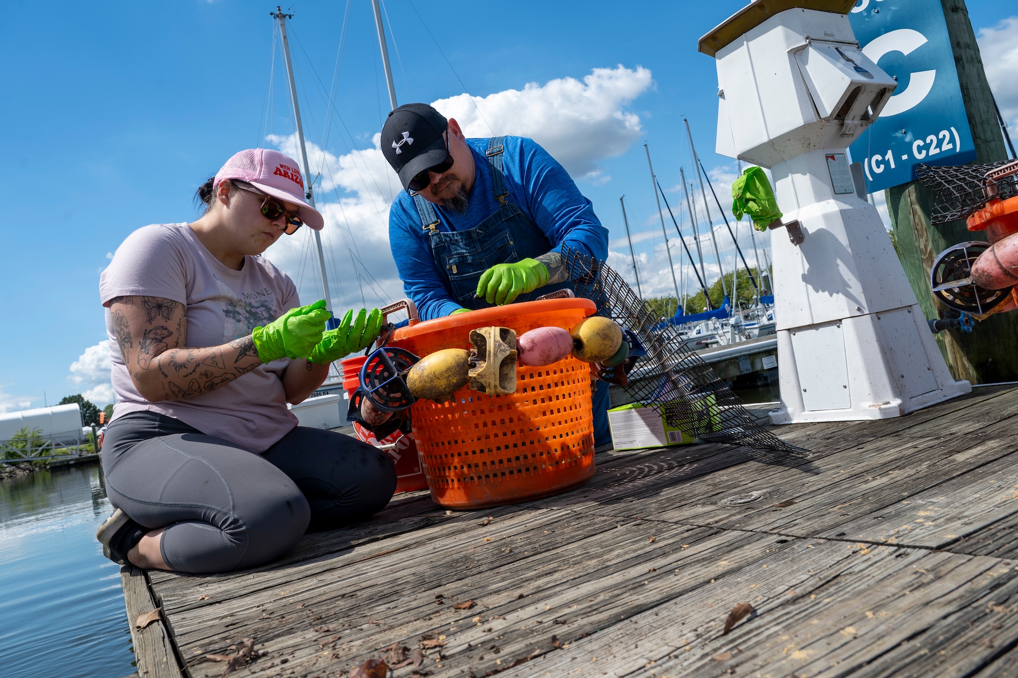 Sarah Payne, left, a manpower analyst with the U.S. Air Force’s 11th Civil Engineer Squadron, and Ryan Soens, chief of environmental management with the 11th CES, count and place young mussels into a bucket at Joint Base Anacostia-Bolling, Washington, D.C., Aug. 22, 2025. The 11th CES partnered with the National Fish and Wildlife Foundation and the Anacostia Watershed Society to release the mussels, which help clean the water by filtering excess nutrient pollutants. Located at the confluence of the Potomac and Anacostia Rivers, which empty into the Chesapeake Bay watershed, JBAB provides an ideal location for the release initiative. (U.S. Air Force photo by Hayden Hallman)