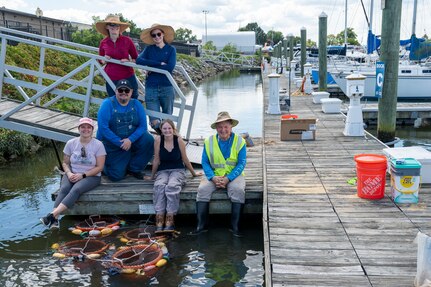 Members of the U.S. Air Force’s 11th Civil Engineer Squadron gather for a group photo next to the young mussels that they released into the Potomac River at Joint Base Anacostia-Bolling, Washington, D.C., Aug. 22, 2025. The 11th CES partnered with the National Fish and Wildlife Foundation and the Anacostia Watershed Society to release the mussels, which help clean the water by filtering excess nutrient pollutants. Located at the confluence of the Potomac and Anacostia Rivers, which empty into the Chesapeake Bay watershed, JBAB provides an ideal location for the release initiative. More than 1,000 young mussels were released during the project. (U.S. Air Force photo by Hayden Hallman)