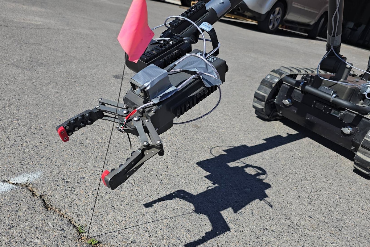 The arm of a robotic system reaches out to a staked flag.