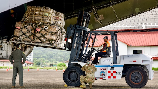 A forklift operator transports a palletized load from the C-5’s rear cargo ramp.