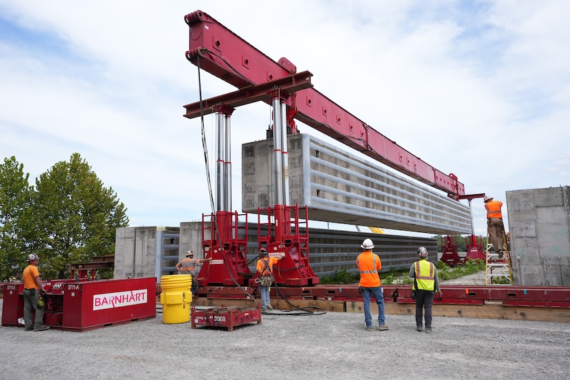 SPRING CITY, Tenn. — Barnhart crew members use a hydraulic power system to lift a prefabricated wall beam onto a barge for delivery to the Chickamauga Lock Replacement Project’s upstream approach wall contract near Watts Bar Dam Aug. 28, 2025. (USACE photo by Noe Gonzalez)
