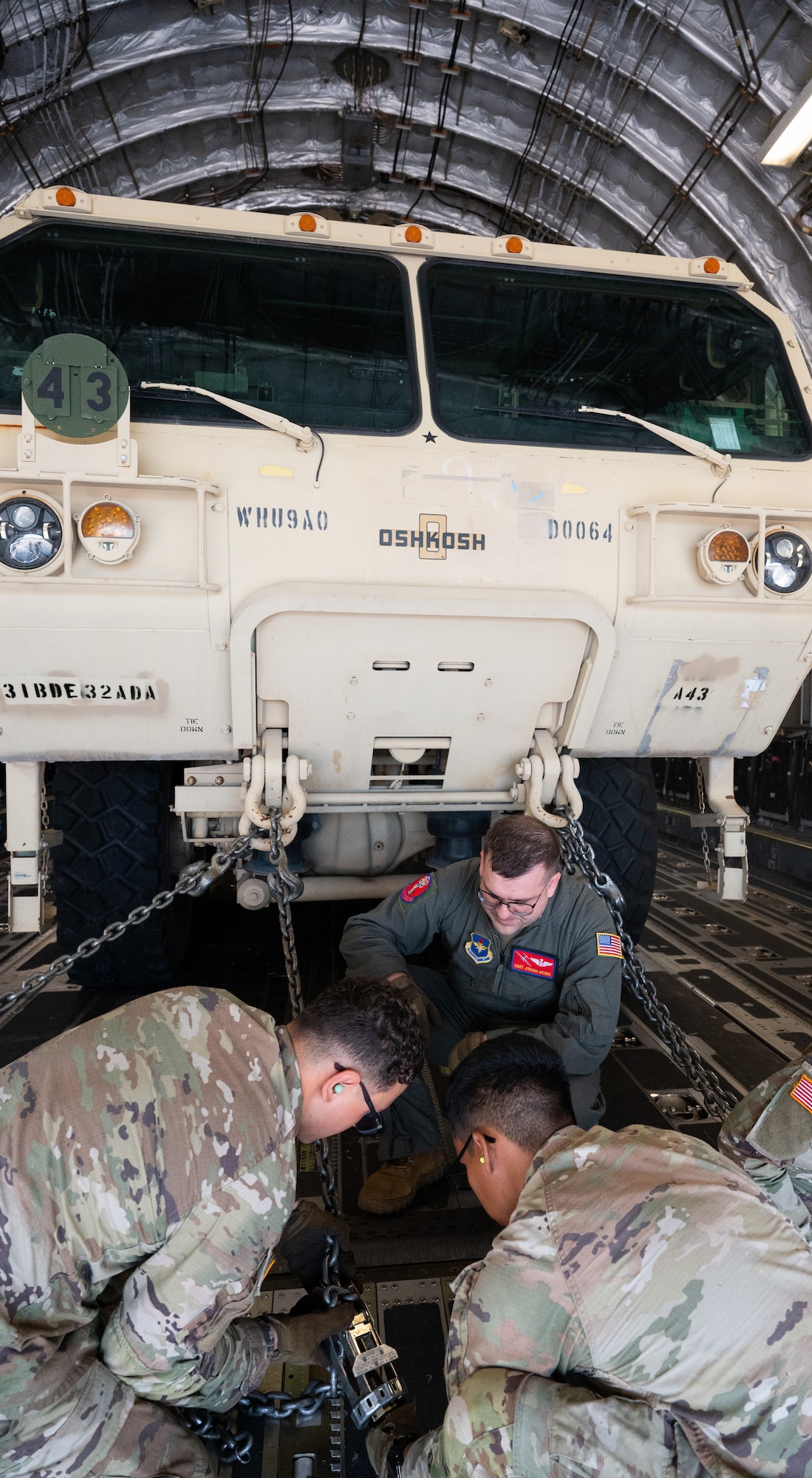 Staff Sgt. Joshua Moore (center), 58th Airlift Squadron loadmaster, instructs U.S. Army Soldiers from Alpha Battery, 3-2 Air Defense Artillery, 31st ADA Brigade, 32 Air and Missile Defense Command on how to load their vehicles onto a C-17 Globemaster III aircraft for a training event at Altus Air Force Base, Okla., Aug. 20, 2025. Soldiers were taught how to apply restraints to their vehicles, and were given an explanation on where to put the restraints in order to ensure the equipment was secure for flight operations. (U.S. Air Force photo by Tech. Sgt. Hailey Haux)