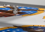 A cutting tool cuts next to art work printed on a white sheet of foam board.