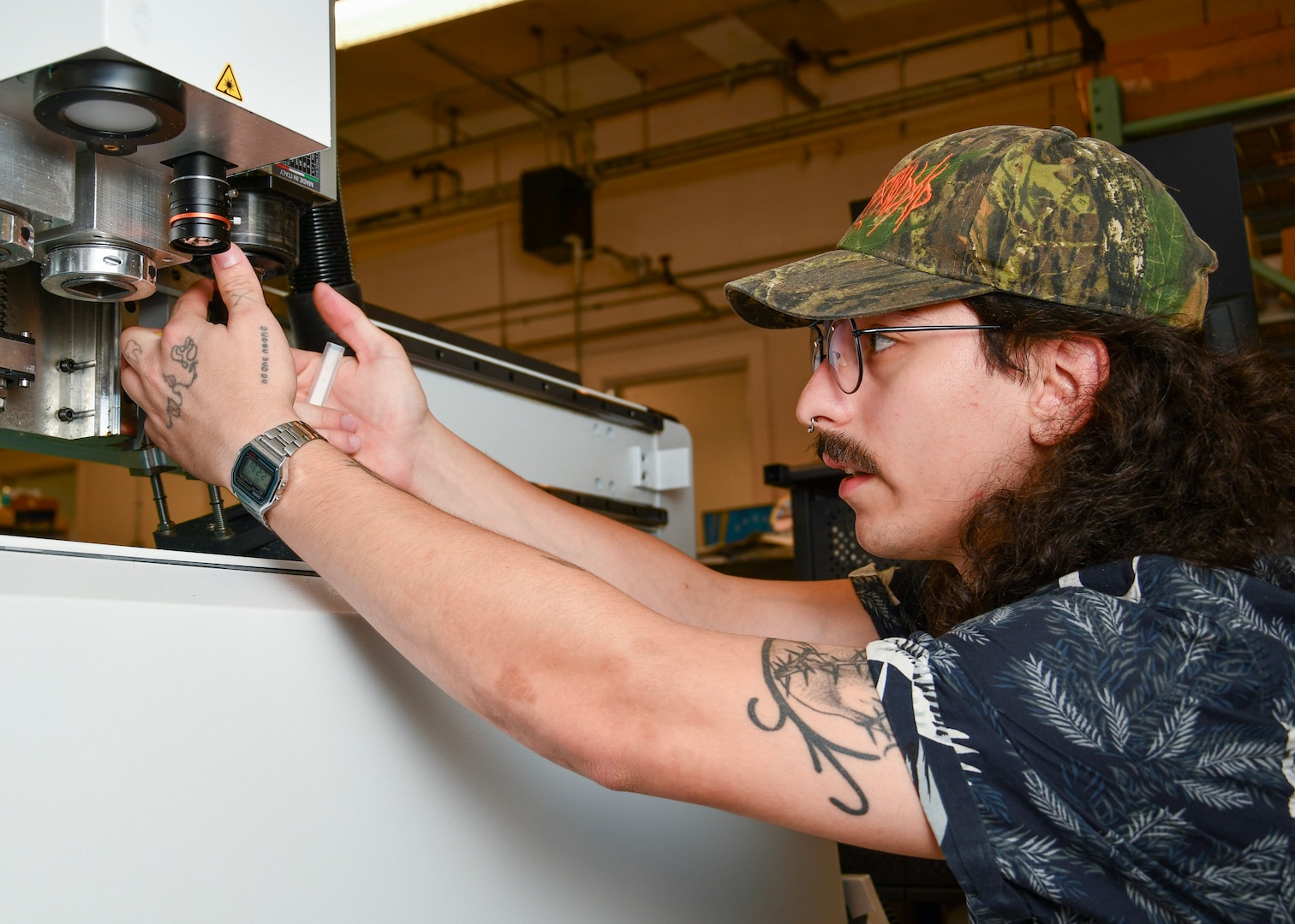 A man uses both hands to remove a cutting tool from a flat bed cutter.