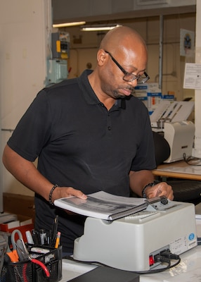 A man operates a manual binding machine.