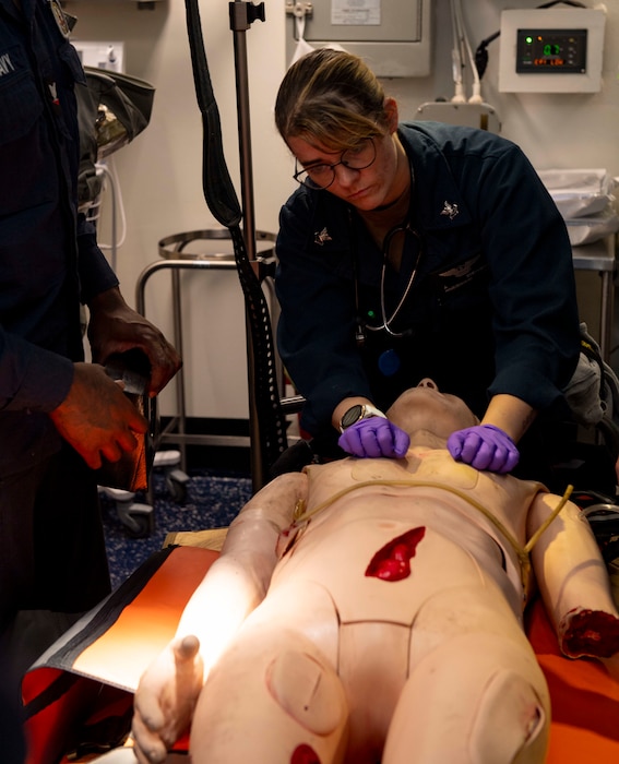 Hospital Corpsman 2nd Class Jordan Stephens, assigned to Wasp-class amphibious assault ship USS Boxer (LHD 4), and a native of Benton, Louisiana, preforms preliminary checks on a simulated patient in the main battle dressing station during a mass casualty drill Aug. 14, 2025. Boxer is currently homeported in Naval Base San Diego. (U.S. Navy photo by Mass Communication Specialist 3rd Class Tyler Miles)
