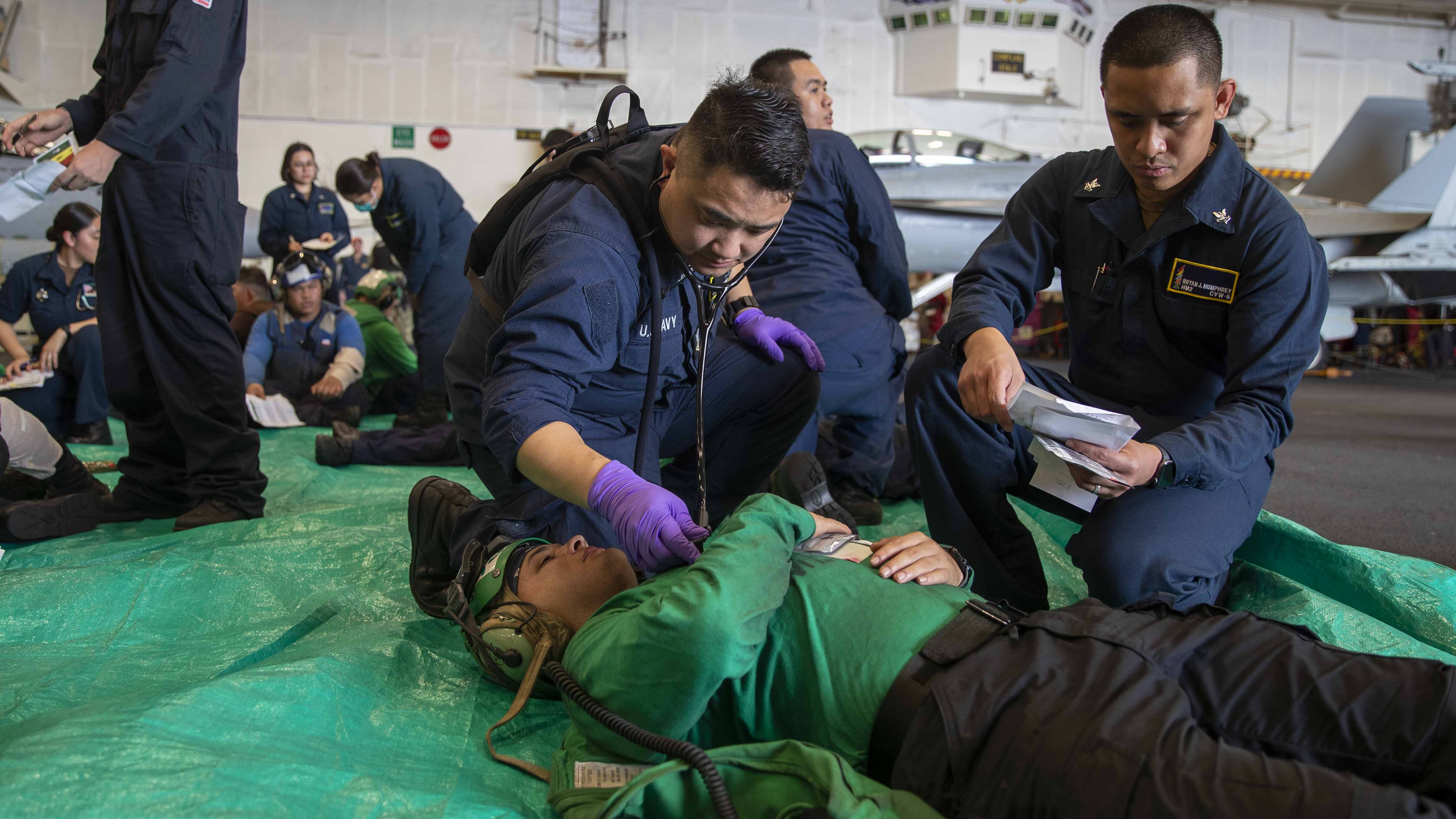 Chief (Select) Hospital Corpsman Ellis Eid, left, from West Fargo, North Dakota, assigned to medical department, and Hospital Corpsman 2nd Class Bryan Humphrey, from Belleville, Illinois, assigned to Carrier Air Wing (CVW) 5, assess a simulated patient in the hangar bay of Nimitz-class aircraft carrier USS George Washington (CVN 73) during a mass casualty drill while underway in the Philippine Sea, Aug. 21, 2025. George Washington is the U.S. Navy’s premier forward-deployed aircraft carrier, a long-standing symbol of the United States’ commitment to maintaining a free and open Indo-Pacific region, while operating alongside allies and partners across the U.S. Navy’s largest numbered fleet. (U.S. Navy photo by Mass Communication Specialist 2nd Class Bruce Morgan)