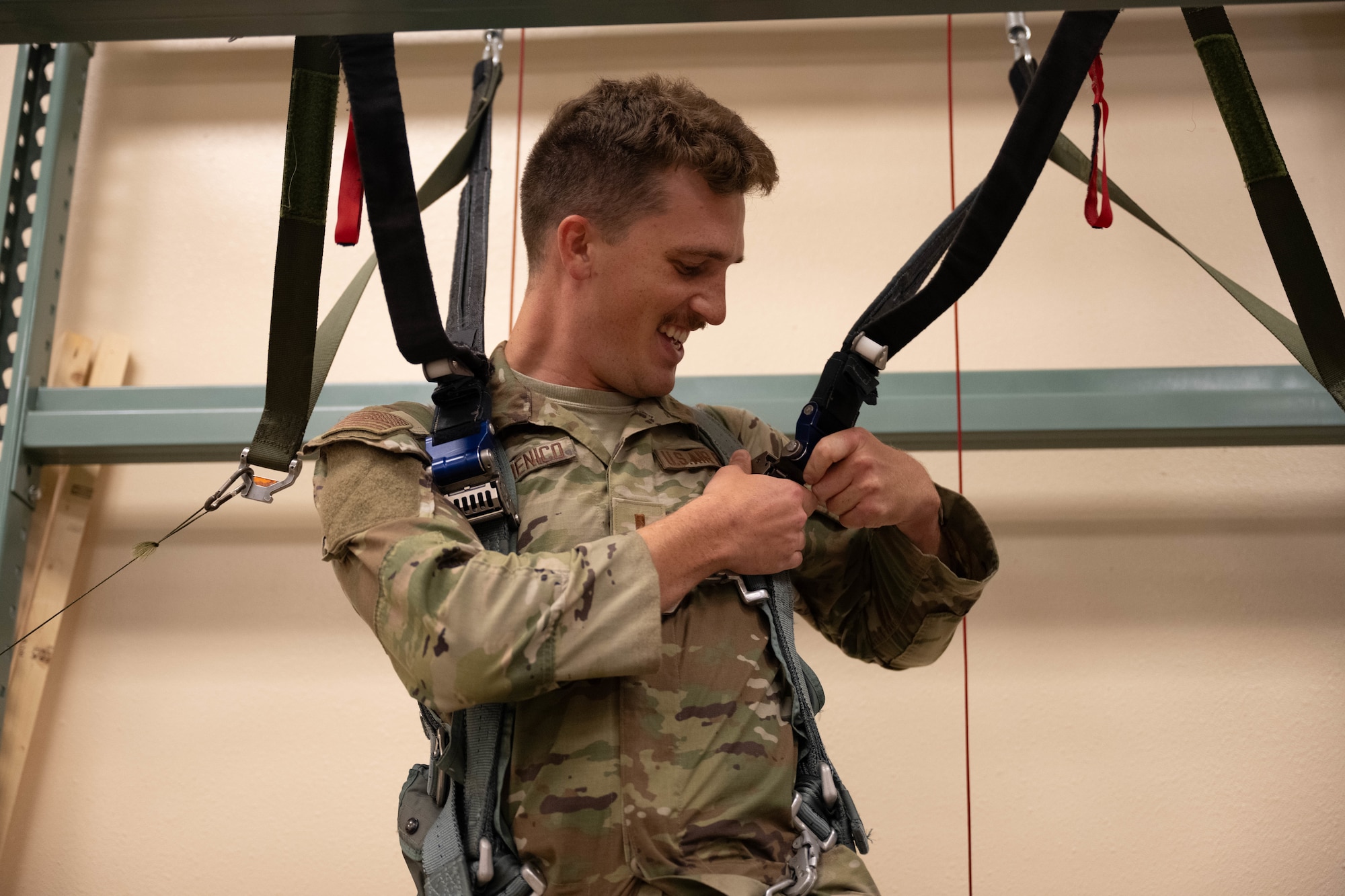 U.S. Air Force 2nd Lt. Nicholas Dedomenico, 47th Student Squadron student pilot, fastens a parachute harness at Laughlin Air Force Base, Texas, Aug. 22, 2025.  Dedomenico received a hands on demonstration how pilots practice descent landing techniques while parachuting. (U.S. Air Force photo by Airman 1st Class Darryl Keith.)