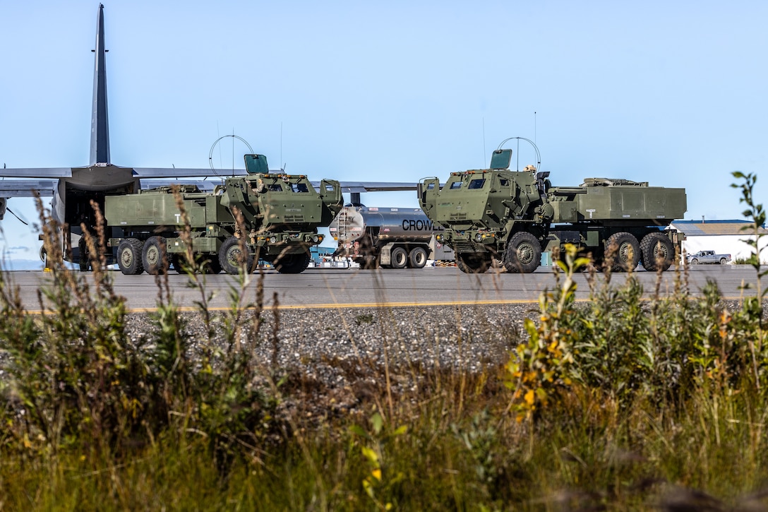 High Mobility Artillery Rocket systems sit along a runway during High Mobility Artillery Rocket System (HIMARS) training as part of ARCTIC EDGE 2025 (AE25) at Kotzebue, Alaska, Aug. 19th, 2025. Specialized Arctic training generates valuable lessons learned for warfighters and enablers ensuring they can execute their assigned missions in any environment. AE25 is a NORAD and U.S. Northern Command-led homeland defense exercise designed to improve readiness, demonstrate capabilities and enhance Joint and Allied Force interoperability in the Arctic. (U.S. Marine Corps Photo by Lance Cpl. Edward Spears)