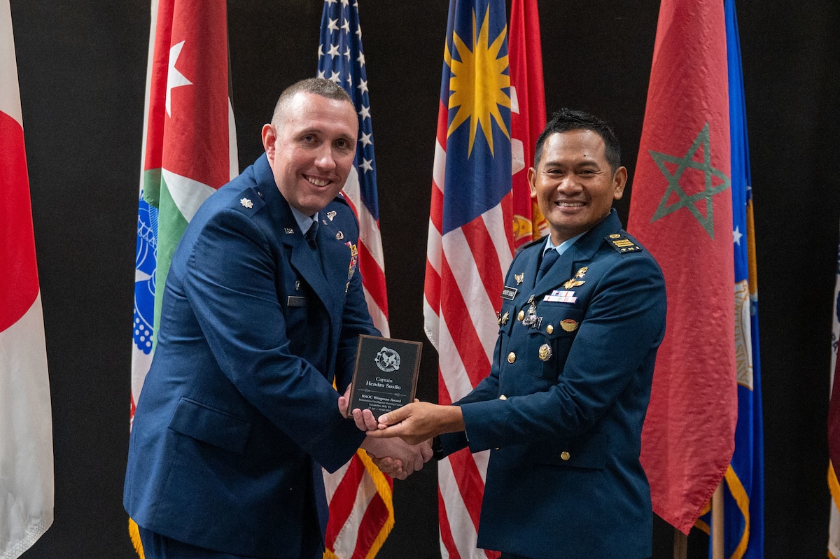 U.S. Air Force Lt. Col. Christopher Cardinale, 313th Training Squadron commander, presents Indonesian Air Force Capt. Hendro Susilo, International Intelligence Applications Officer Course student with the Wingman Award at the Powell Event Center, Goodfellow Air Force Base, Texas July 18, 2025. The Wingman Award is peer-nominated and presented to the student who best exemplifies teamwork, support, and camaraderie throughout the course. (U.S. Air Force photo by Airman 1st Class James Salellas)