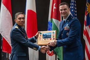 Royal Malaysian Air Force Maj. Rozaimi Bin Jamaludin, a student in the International Intelligence Applications Officer Course, presents U.S. Air Force Capt. Ryan Best, International Intelligence Training Center flight commander, with a plaque on behalf of the class at the Powell Event Center, Goodfellow Air Force Base, Texas, July 18, 2025. This iteration of the course included officers from 10 different countries, representing a diverse coalition of global military partners. (U.S. Air Force photo by Airman 1st Class James Salellas)