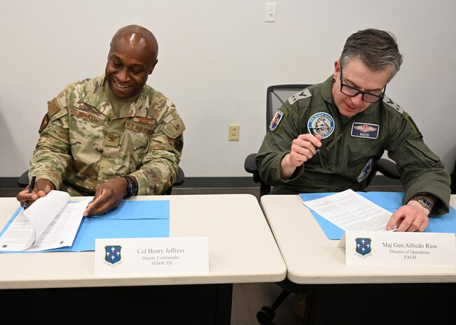 U.S. Air Force Col. Henry Jeffress, Air Forces Southern deputy commander, left, and Chilean (FACh) Air Force Maj. Gen. Alfredo Ríos, FACh director of operations, right, sign agreements during their annual Airman-to-Airman Talks at Davis-Monthan Air Force Base, Arizona, Aug. 28, 2025. Jeffress and Ríos signed agreements for future training, exercises and operations and to Strengthen professional and personal relationships between the two air forces. (U.S. Air Force photo by Staff Sgt. Abbey Rieves)