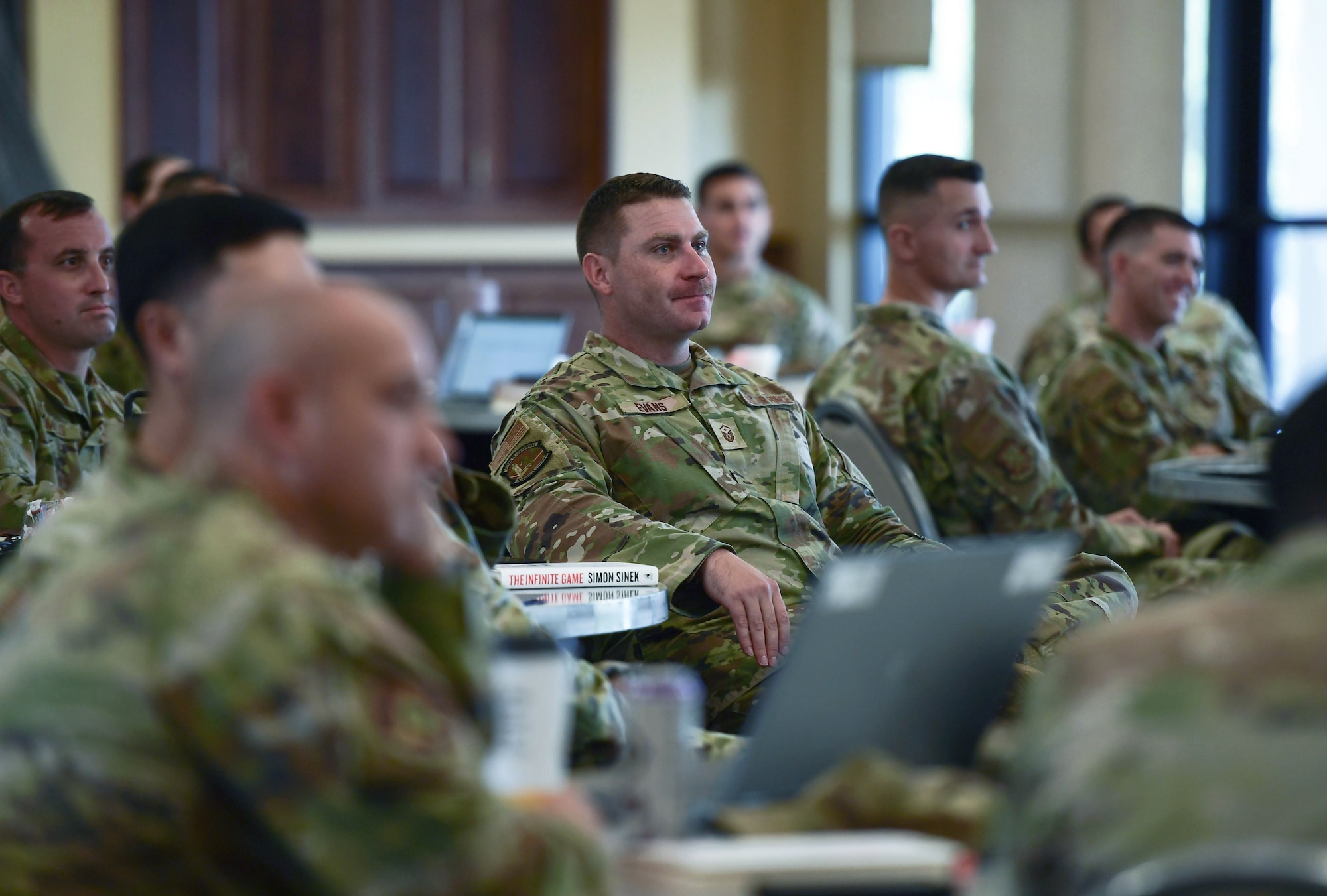 A man in military uniform sits among a group of people.