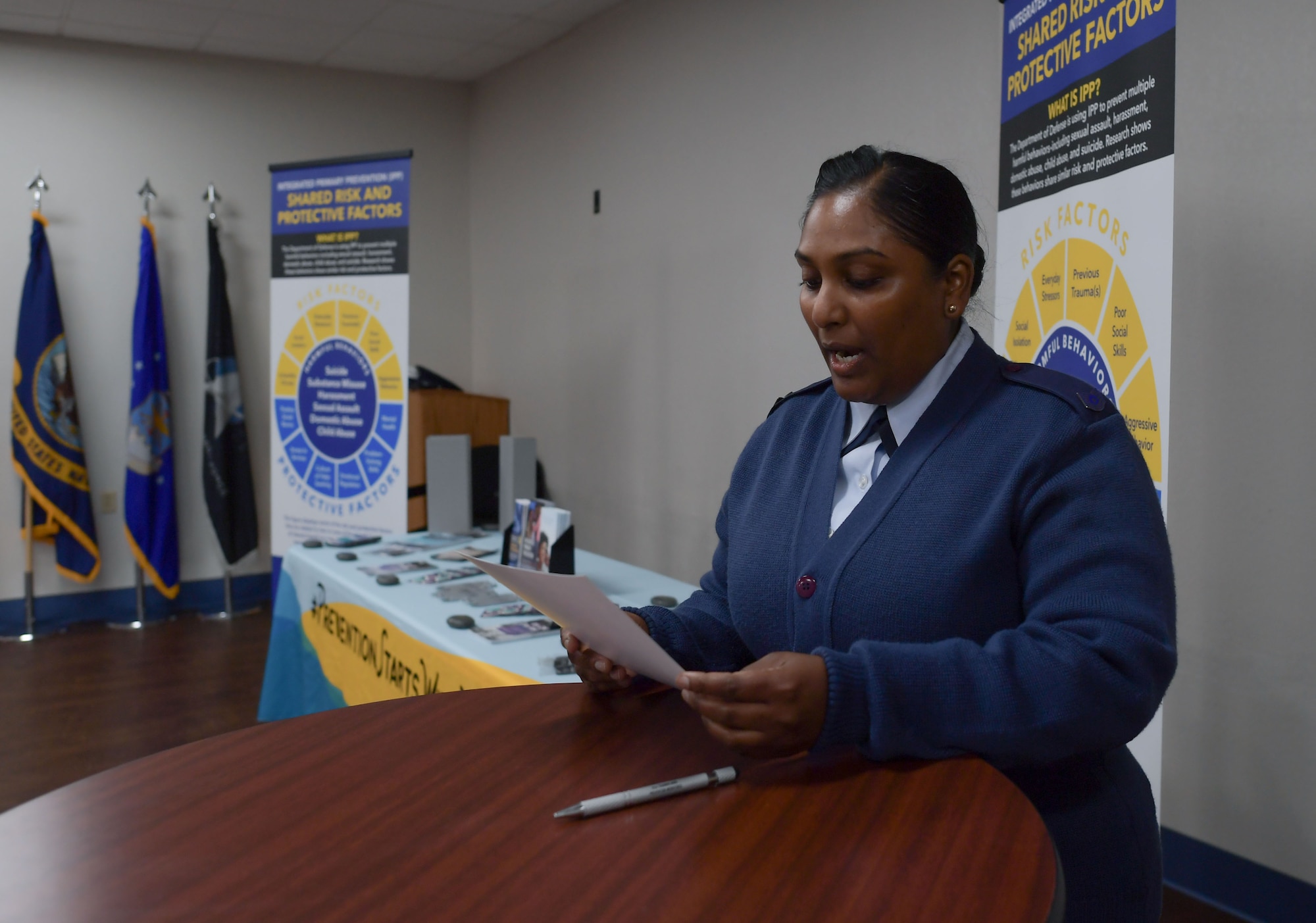 A woman in military uniform reads from a piece of paper that she is holding.
