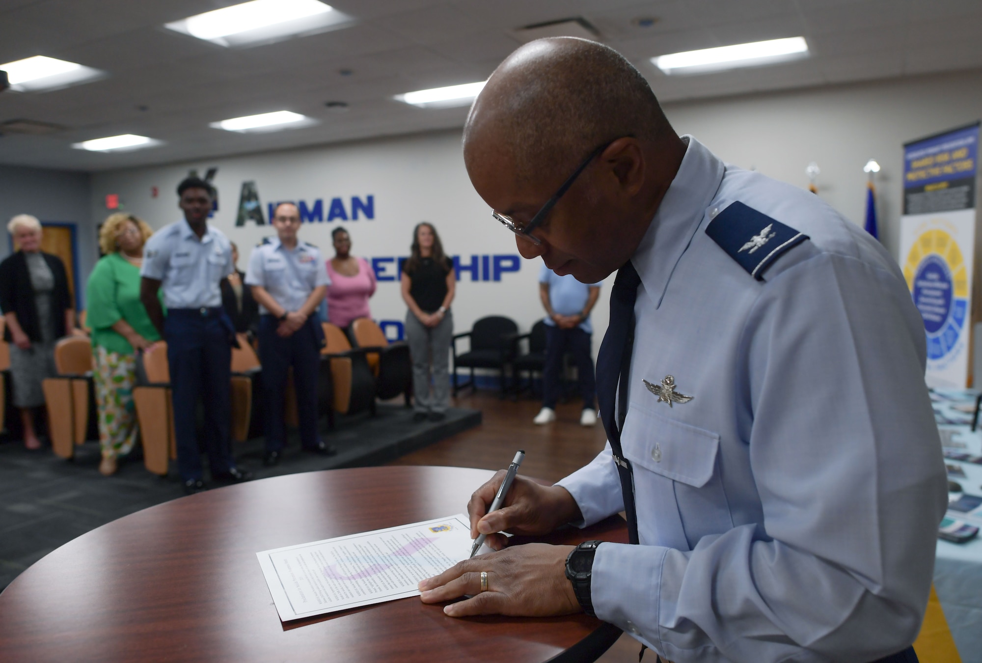 A man in military uniform signs a document