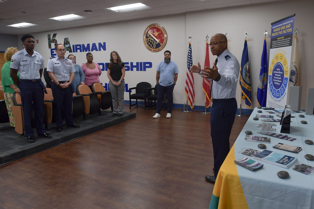 A man in military uniform speaks to a group of people.