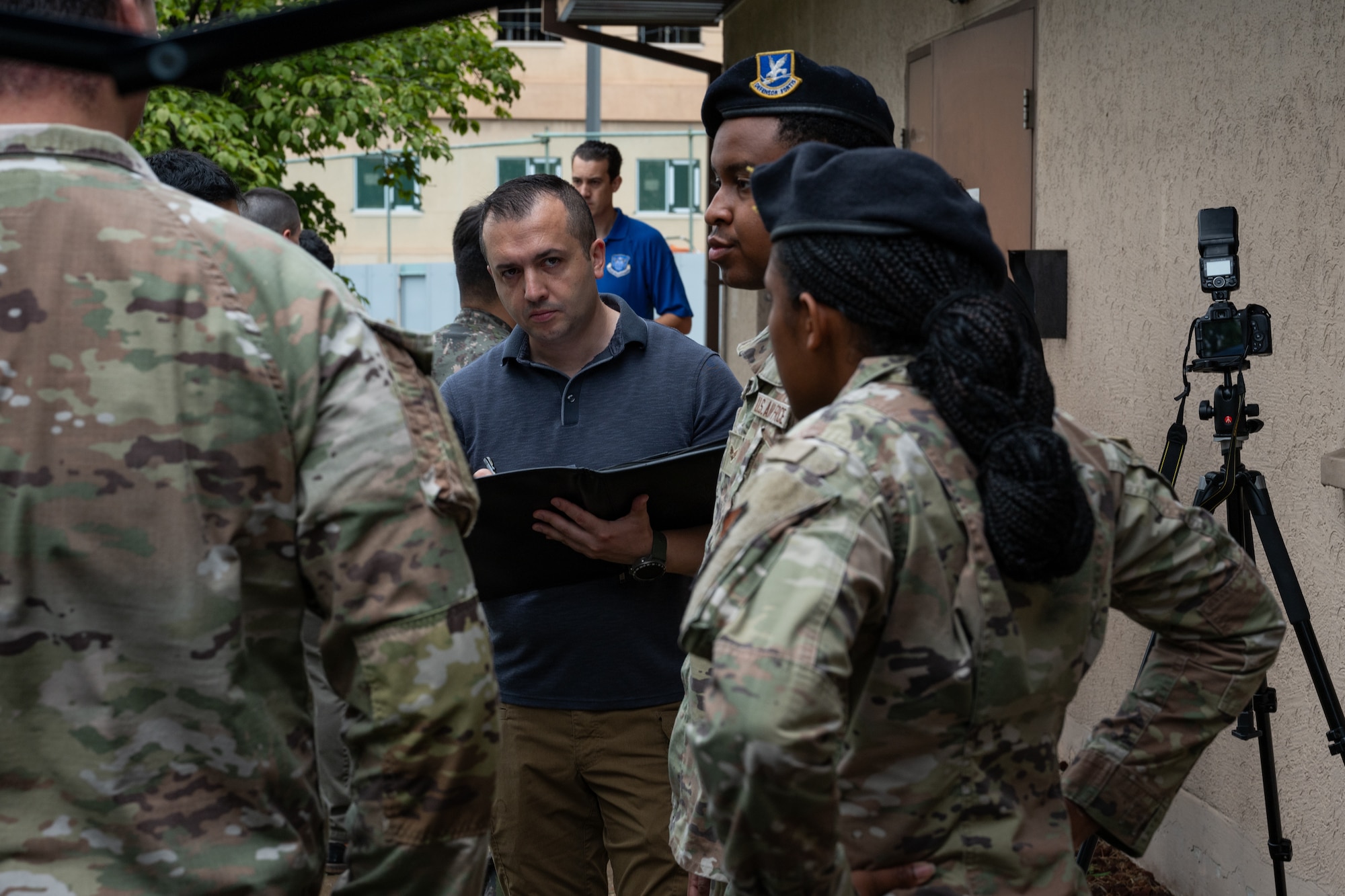 A crime scene investigator takes notes of a statement from defenders acting as first responders during a training scenario.