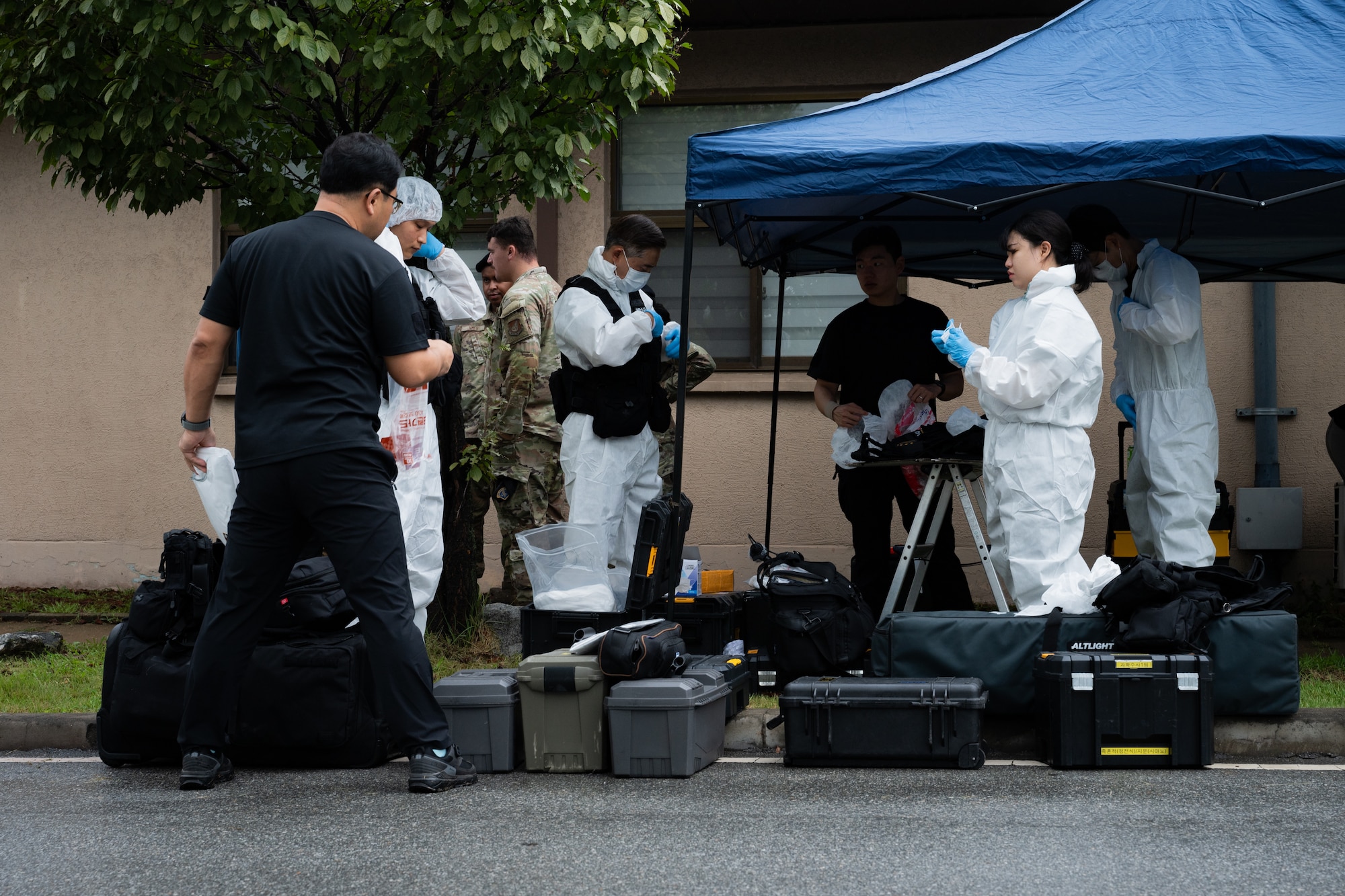 Crime scene investigators put on their gear before entering a training scene.