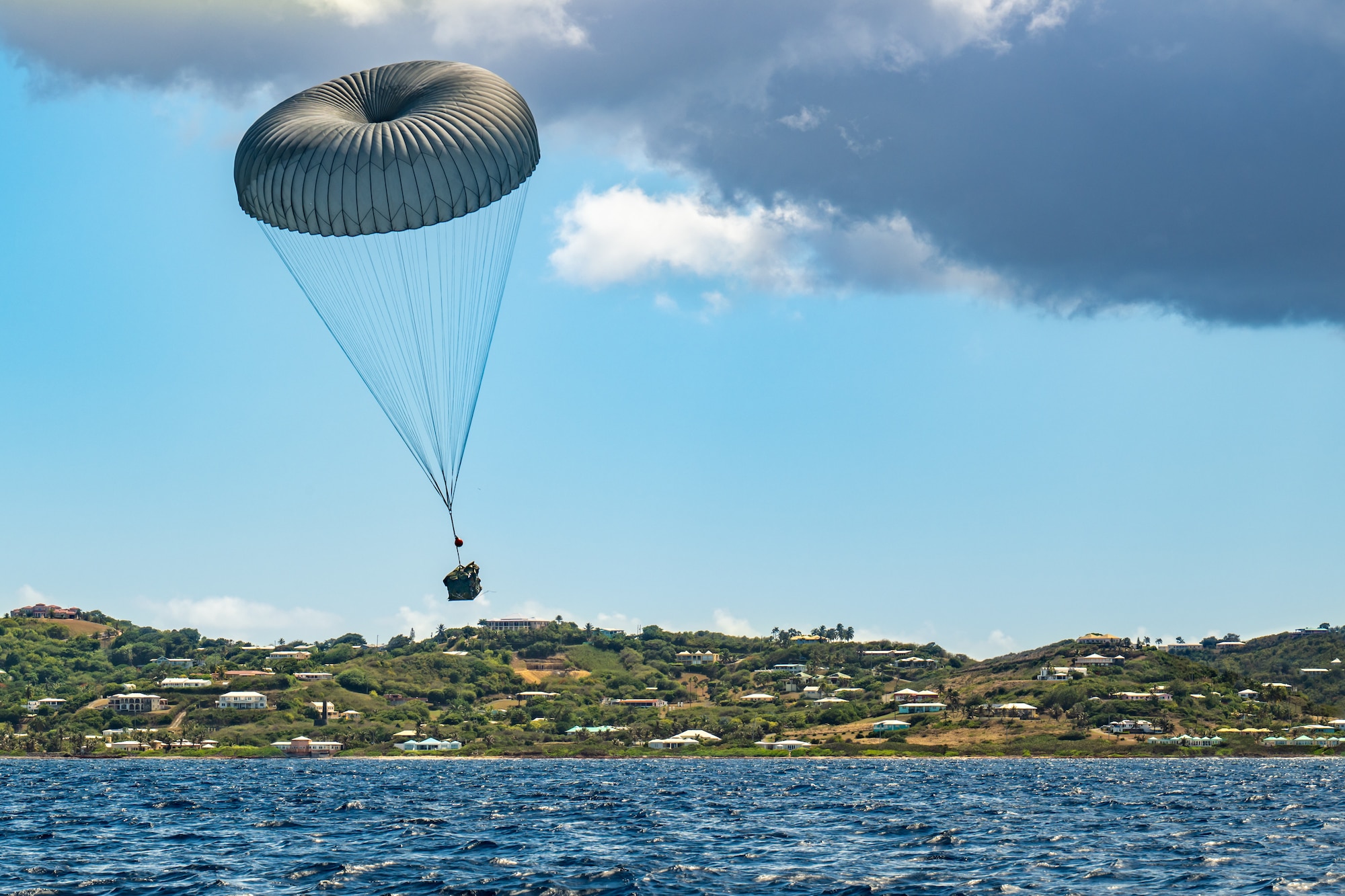 An inflatable boat bundle parachutes into the Caribbean Sea after being airdropped from a Kentucky Air National Guard C-130J Super Hercules off the coast of St. Croix, U.S. Virgin Islands, Aug. 29, 2025 as part of Emerald Warrior 25.2, a large-scale special operations exercise staged in multiple locations by Air Force Special Operations Command. St. Croix provides an ideal environment for testing littoral and maritime capabilities, simulating many of the geographic features that Airmen may encounter when deployed around the world to project air power in unfamiliar or contested environments. (U.S. Air National Guard photo by Dale Greer)
