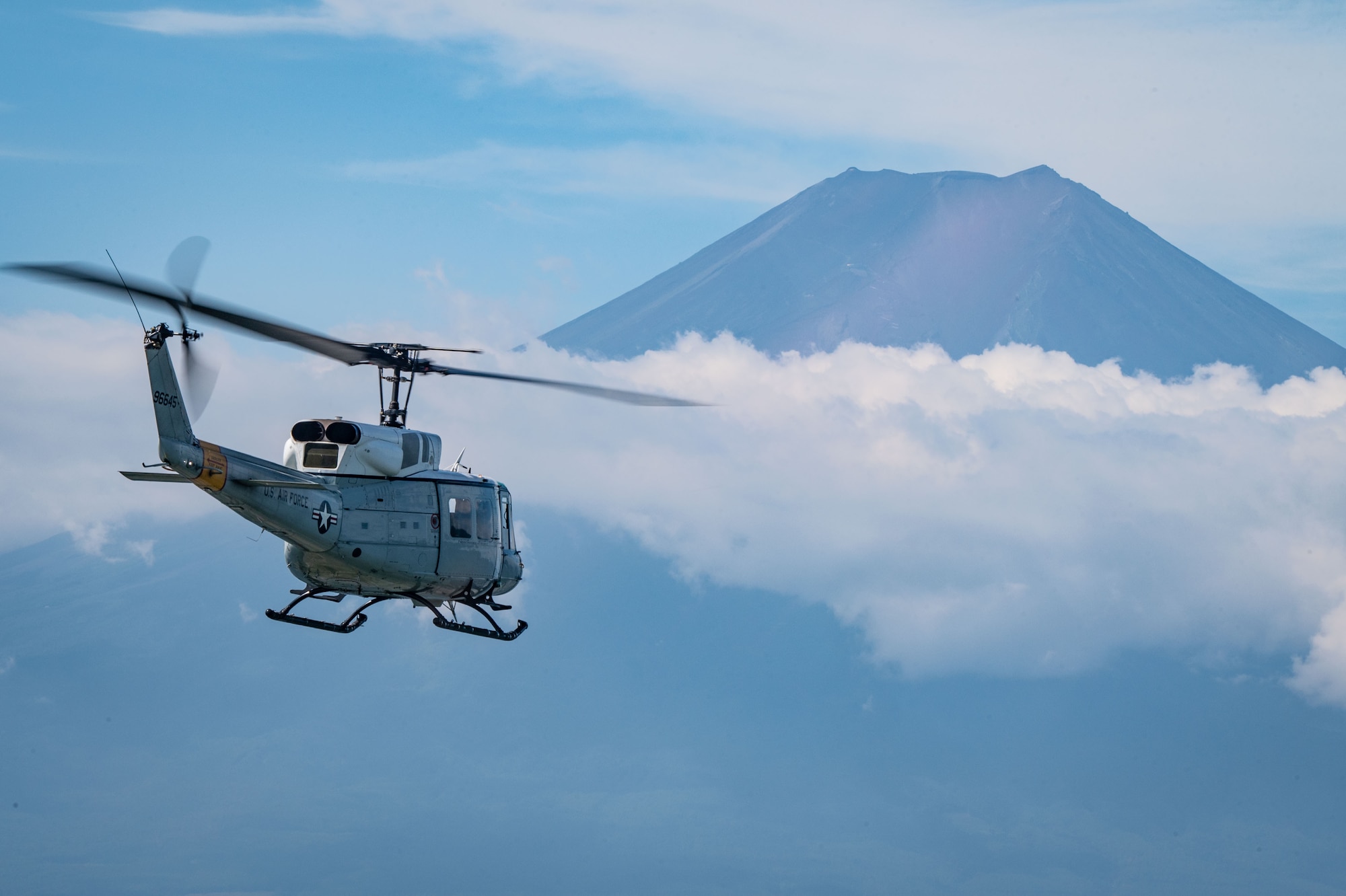 A helicopter flies in front of a mountain