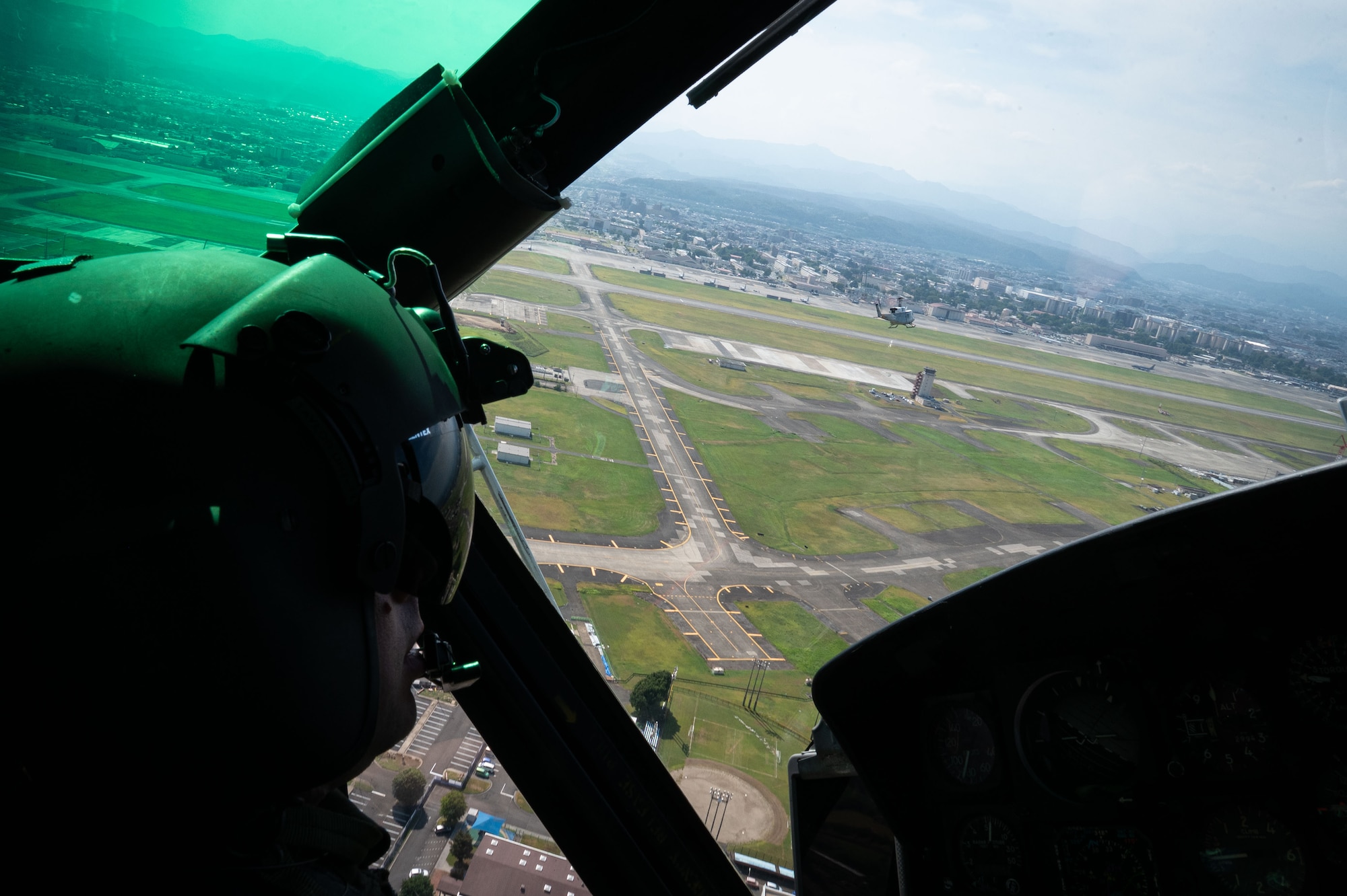 Two helicopters approach an airfield.