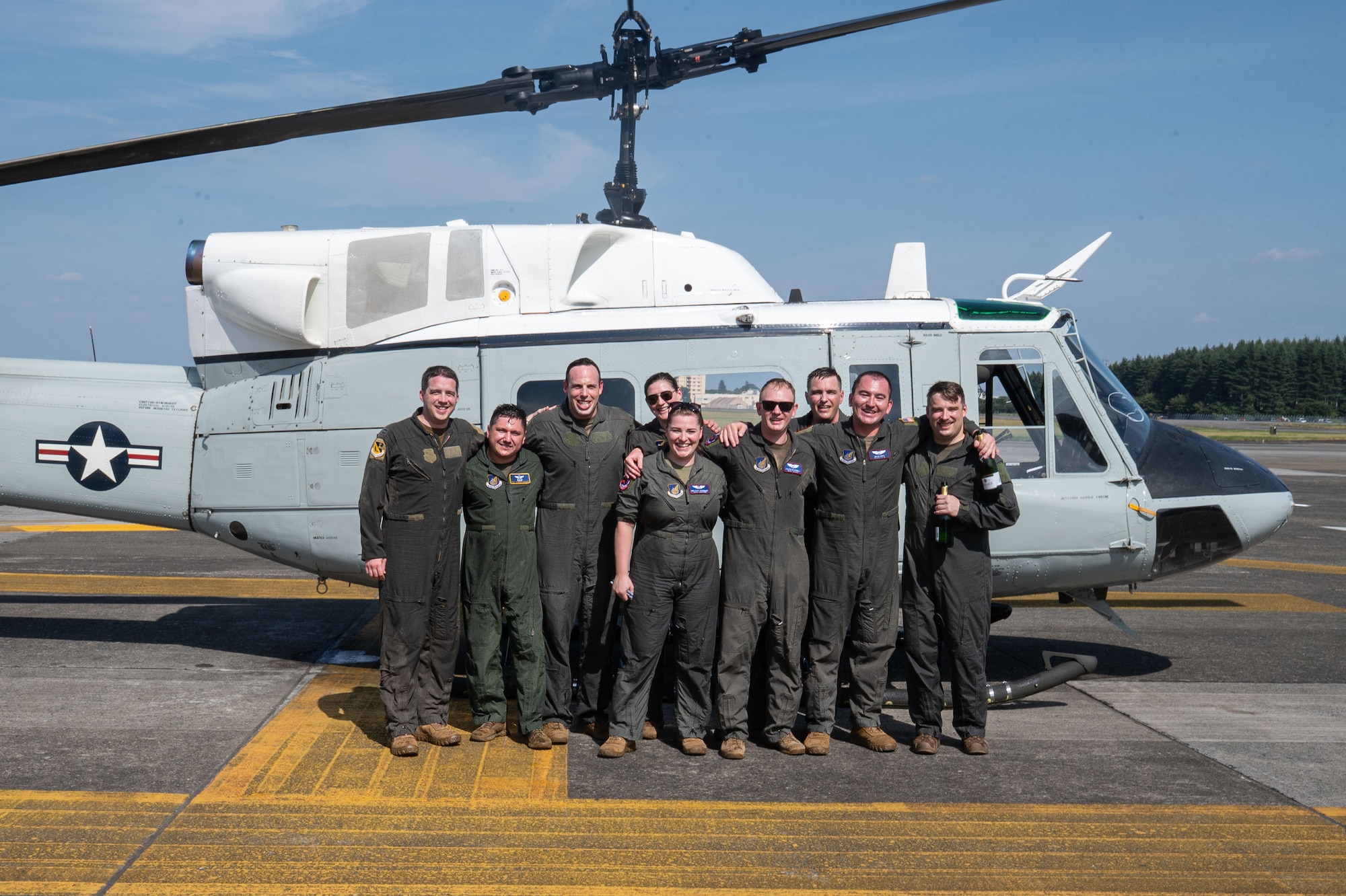 U.S. servicemembers pose in front of a helicopter