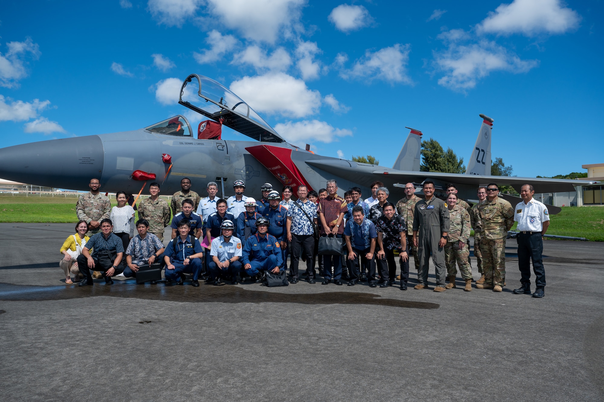 Airmen and Government of Japan officials pose for a photo in front of an F-15C Eagle