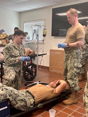 Hospital Corpsman 2nd Class Clayton VanStry prepares to administer a unit of fresh whole blood to Hospital Corpsman Andres Valenzuela while Lt. Rhett Henrich observes, during training at U.S. Naval Hospital Guantanamo Bay, July 24, 2025. Whole blood transfusion capability provides a critical life-saving option in combat and austere environments, directly supporting operational readiness. (U.S. Navy photo by Hospital Corpsman 2nd Class Shakirah Peterson-Wall)