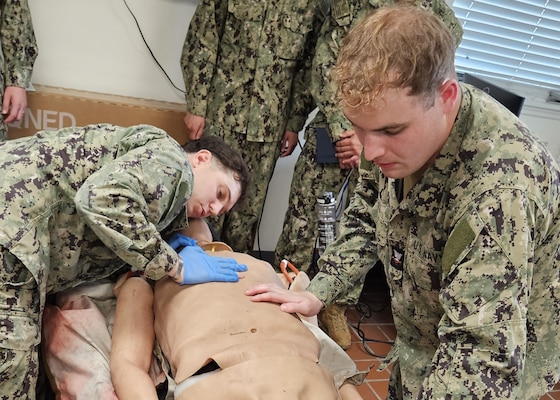GUANTANAMO BAY, Cuba (July 24, 2025) – Hospital Corpsman 2nd Class Clayton VanStry and Hospital Corpsman 3rd Class Ramsey Hall demonstrate how to assess a casualty during tactical combat casualty care training at U.S. Naval Hospital Guantanamo Bay, July 24, 2025. The training program focused on conducting whole blood transfusions to provide critical life-saving care in combat and austere environments, directly supporting operational readiness. (U.S. Navy photo by Capt. Tammy Servies)