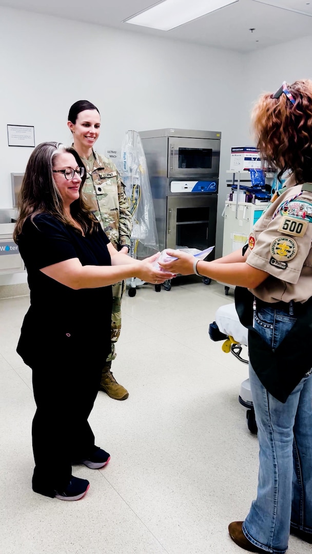 Winn Army Community Hospital ER clinical nurse supervisor Melissa Hungerford accepts one of more than 100 Better Bears from Life Scout Reis Hill as Lt. Col. Brittany Kull, Winn’s chief of hospital education, looks on. Reis created the bears for her Eagle Scout project to help comfort children visiting the ER.
