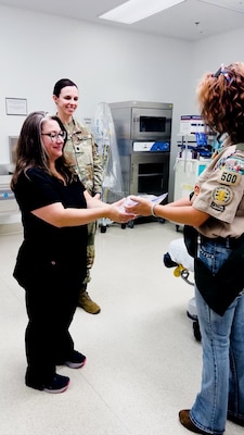 Winn Army Community Hospital ER clinical nurse supervisor Melissa Hungerford accepts one of more than 100 Better Bears from Life Scout Reis Hill as Lt. Col. Brittany Kull, Winn’s chief of hospital education, looks on. Reis created the bears for her Eagle Scout project to help comfort children visiting the ER.