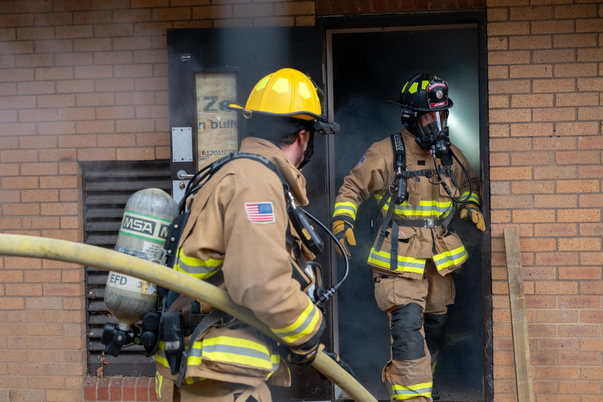 Firefighters exit a smoke-filled building during a joint training exercise