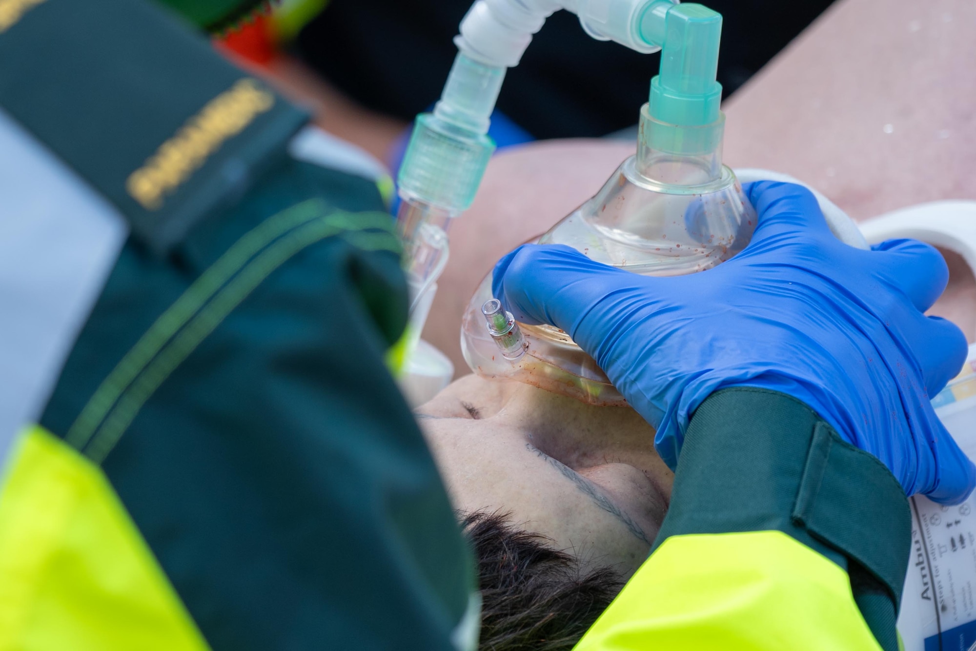A UK paramedic administers oxygen to a simulated casualty