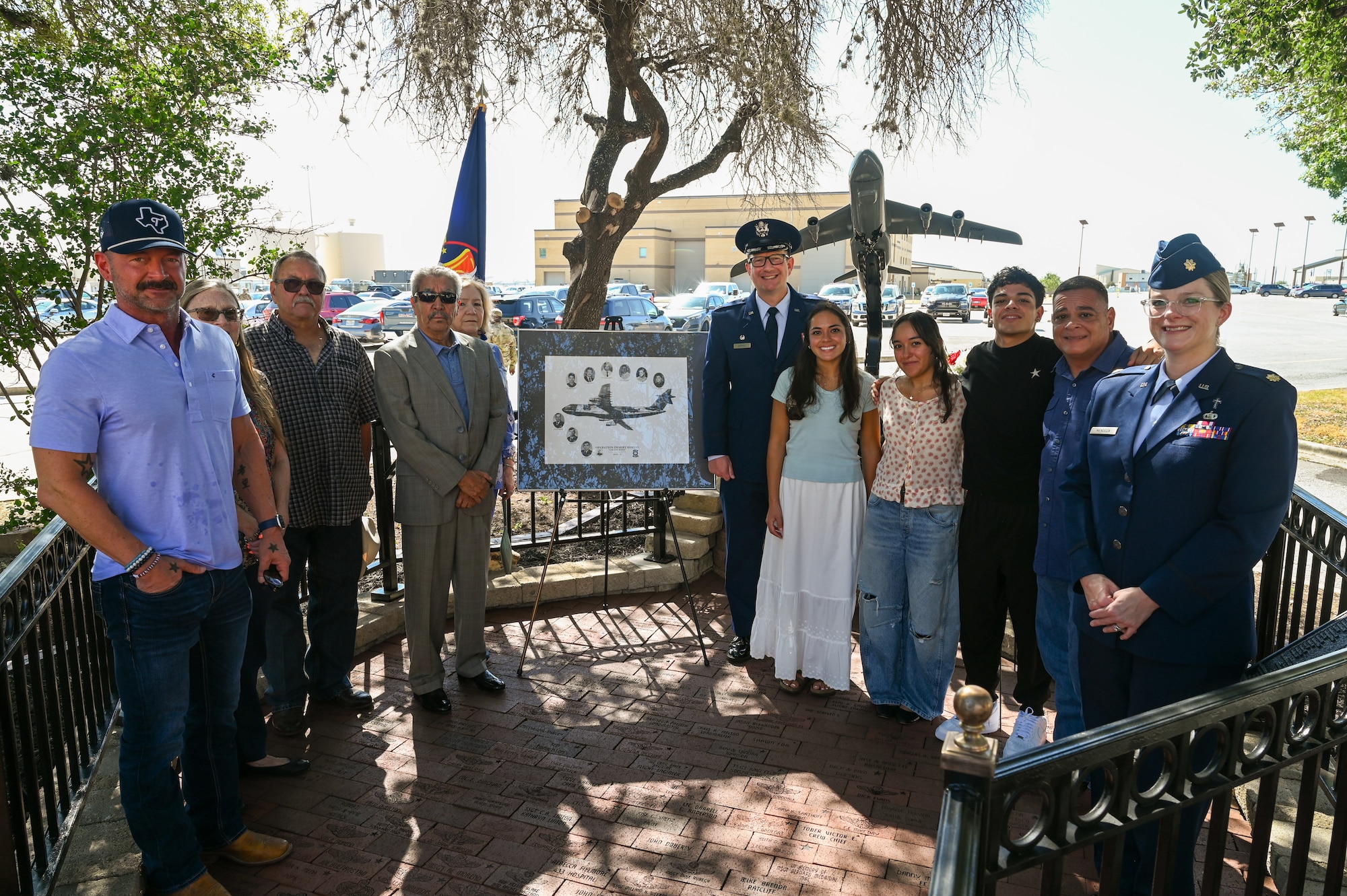 Col. Douglas Jeffrey, 433rd Airlift Wing commander, and Chaplain (Maj.) Heather Mendoza, 433rd Airlift Wing deputy chaplain, pose for a group photo with one of the survivors and family members of the BRAVO-12 crew following a remembrance ceremony outside the 68th Airlift Squadron building on Joint Base San Antonio-Lackland, Texas Aug. 29, 2025.