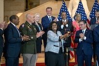 Debra Willett, center, displays the Congressional Gold Medal for the Army’s World War I 369th Infantry Regiment, the “Harlem Hellfighters,” during a ceremony in Emancipation Hall at the U.S. Capitol, September 3, 2025, in Washington.