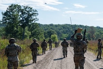 Defender Airmen patrol along a dirt road within Camp Ripley Training Center.