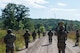 Defender Airmen patrol along a dirt road within Camp Ripley Training Center.
