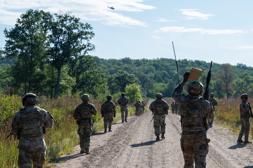 Defender Airmen patrol along a dirt road within Camp Ripley Training Center.