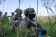 Defender Airmen patrol through foliage.