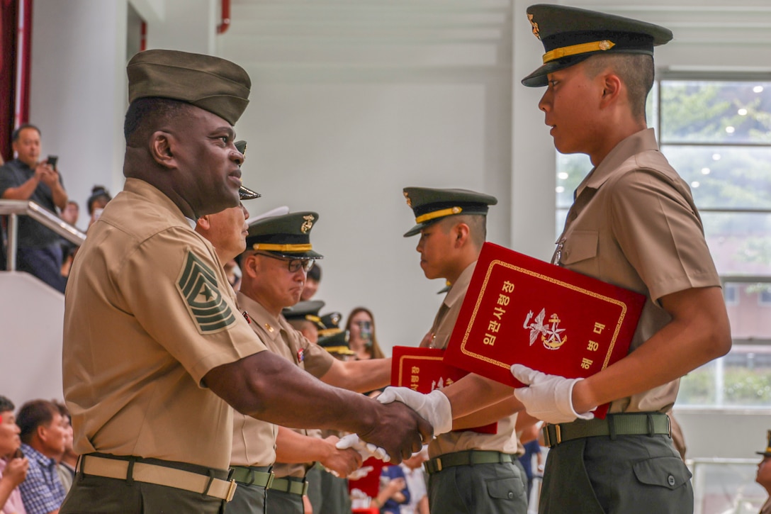 U.S. Marine Corps Sgt. Maj. Ismael G. Bamba, command senior enlisted leader of U.S. Marine Corps Forces Korea, congratulates a graduate at the ROK Marine Corps non-commissioned officer graduation in Pohang, South Korea, on Aug. 8, 2025. The NCO graduation marks the successful completion of rigorous training, where new non-commissioned officers are honored for their leadership skills, discipline, and readiness to lead Marines in the ROK Marine Corps. (U.S. Marine Corps photo by Cpl. Simon Saravia)