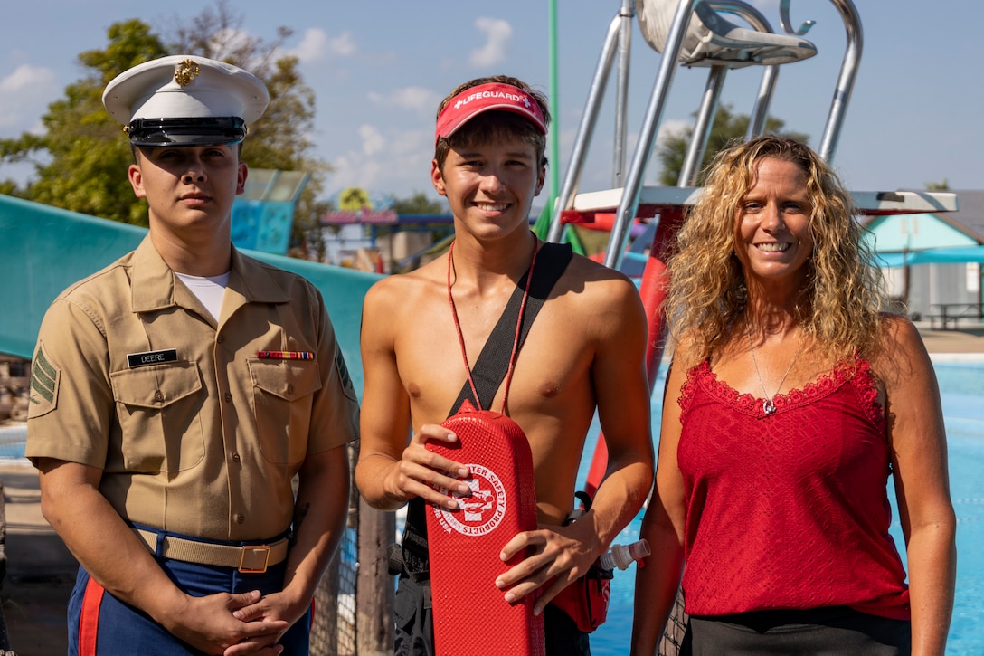 Elijah Buzzard, center, poses for a photo with his recruiter, Sgt. Brandon Deere, left, and his supervisor, Adina Meilner, right, at Paradise Beach Waterpark, Tulsa, Oklahoma, Aug. 15, 2025. Buzzard, a lifeguard at the water park, has been credited for saving multiple lives during the 2025 summer season and is scheduled to attend recruit training at Marine Corps Recruit Depot San Diego, California, this fall. (U.S. Marine Corps photo by Staff Sgt. Lennon Dregoiw)