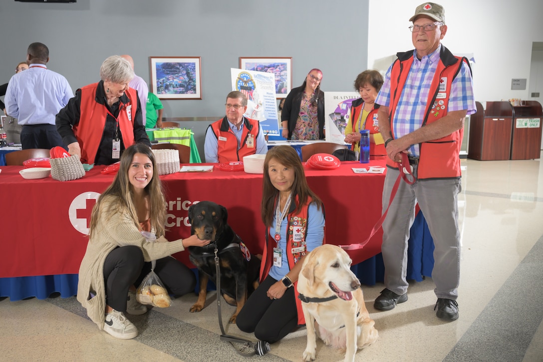 A group of American Red Cross workers and a Defense Logistics Agency employee pose with a comfort dog.