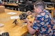A man sitting at a work table inspecting a drone.