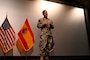 Rear Adm. Rosen stands on a stage explaining to a crowd.