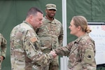 U.S. Air Force Maj. Gen. Gary Keefe, the Adjutant General of the Massachusetts National Guard, coins U.S. Army Lt. Col. Jennifer Green, commander of the 110th Combat Sustainment Support Battalion, in Zagan, Poland, May 23, 2025. Deployed to Poland in October 2024, Soldiers of the 110th CSSB led a multi-component task force responsible for sustaining the continuous flow of critical supplies to NATO allies and partners across eight Eastern European countries.