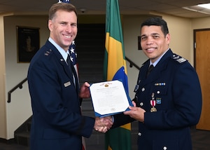 U.S. Air Force Maj. Gen. David Mineau, Air Forces Southern commander, left, presents Brazilian Air Force Col. Leonardo Macedo, foreign liaison officer, right, the Meritorious Service Medal at Davis-Monthan Air Force Base, Arizona, Sept. 4, 2025. For the past year and a half, Macedo provided military advice to Mineau, guided communications and fostered cooperation between the Brazilian and United States Air Forces. (U.S. Air Force photo by Staff Sgt. Abbey Rieves)