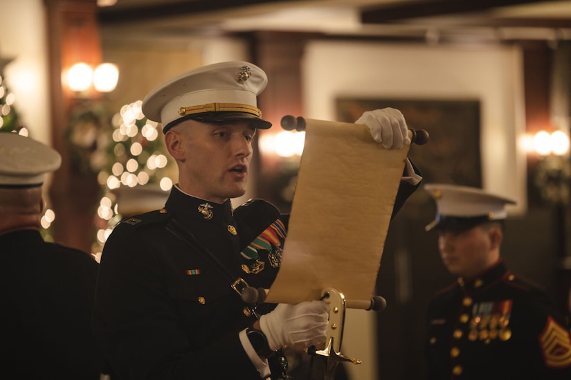 A Marine in a military dress uniform reads from a scroll.