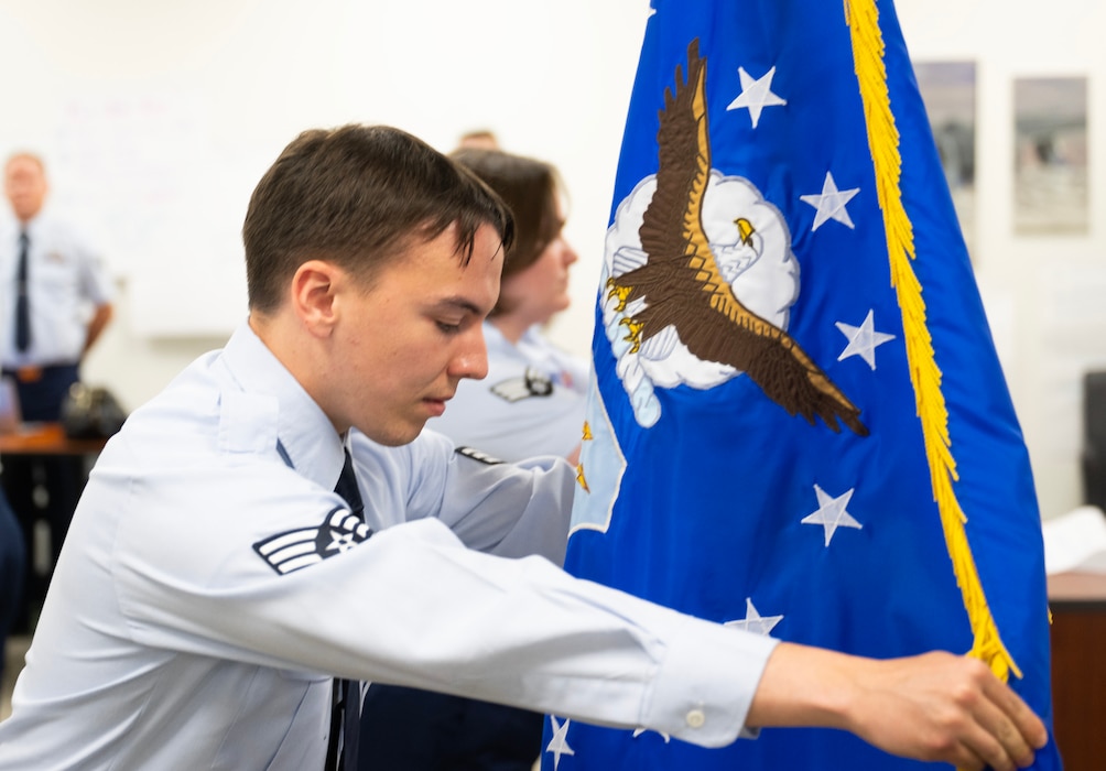 A man in the blue Air Force uniform arranges the Air Force flag.