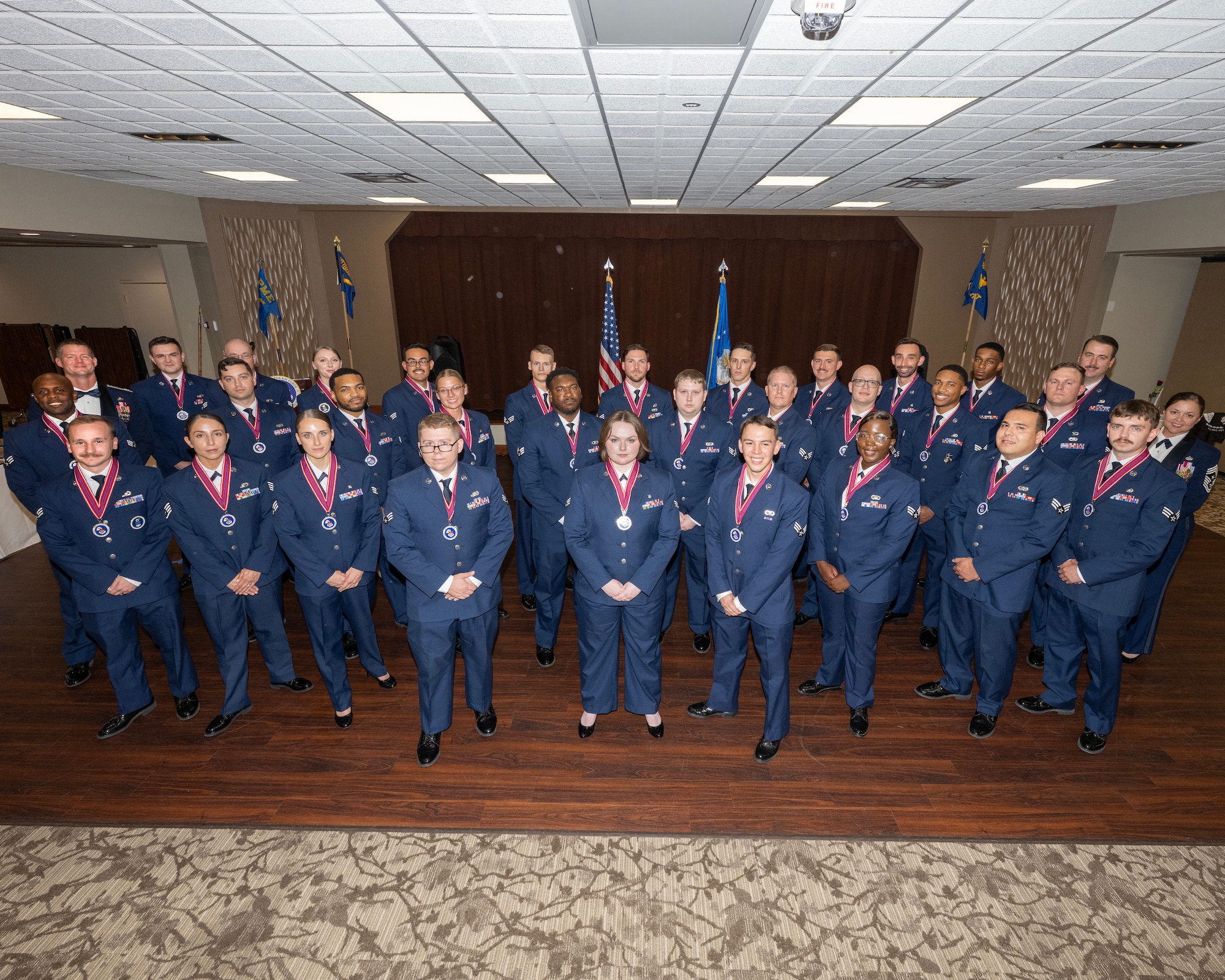A group of Airmen in dress uniform pose for a photos