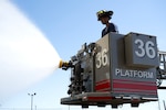 firefighter controls a water nozzle to extinguish a simulated fire.
